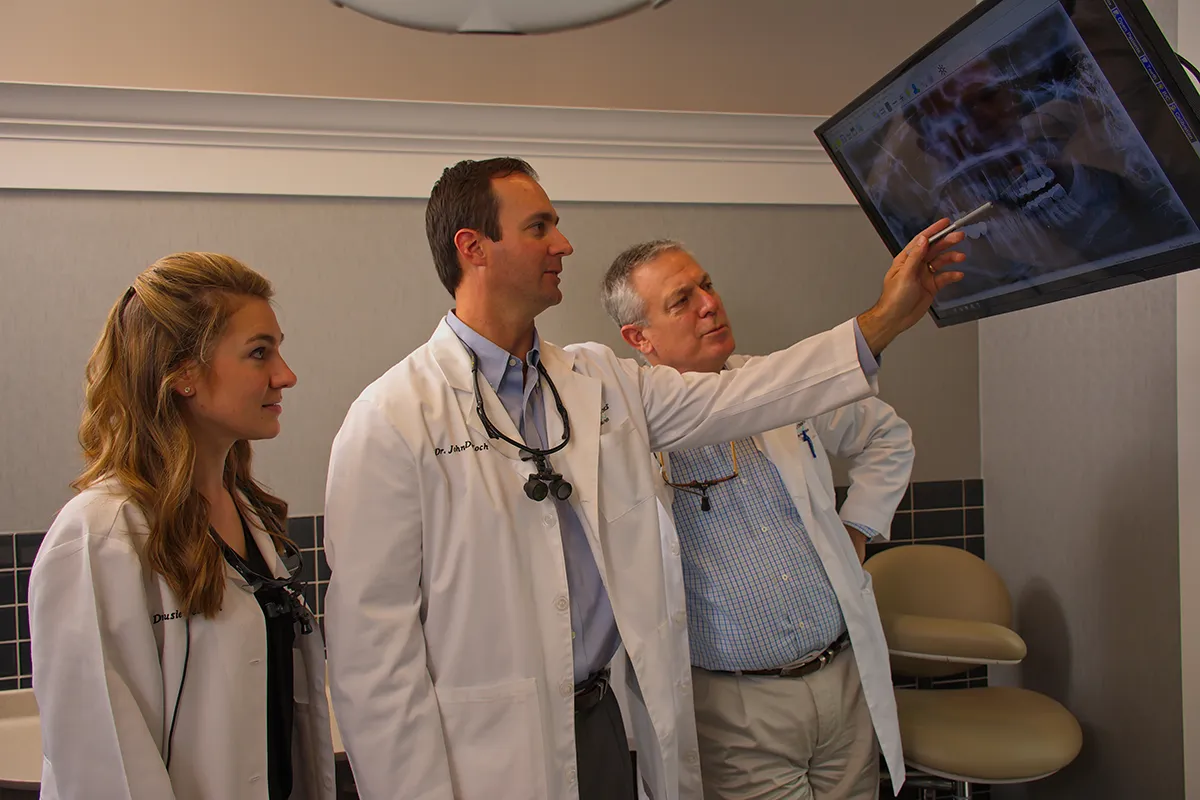 Drs. Susie, John, and Dirk DeKoch reviewing a panoramic x-ray together